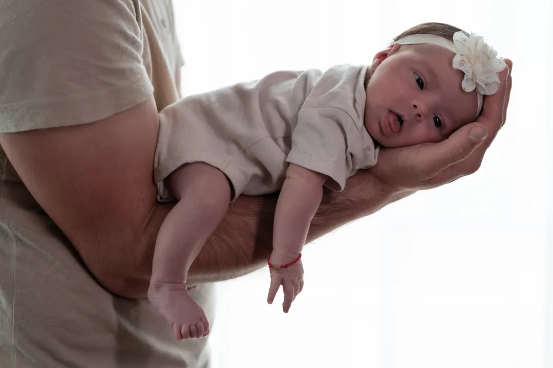 Foto eines Babys, das in der Hand ihres Vaters liegt