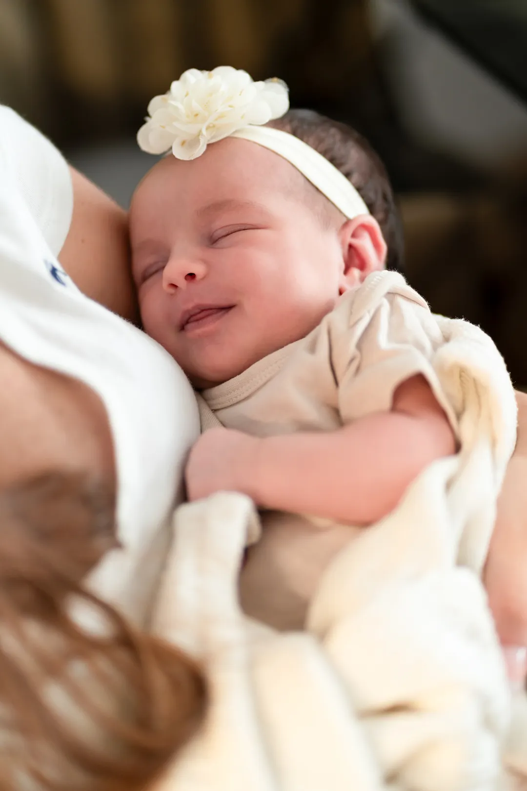 Nahaufnahme eines Babys, das in den Armen ihrer Mutter liegt und lächelt